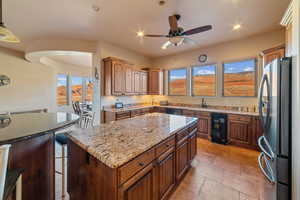 Kitchen with sink, decorative light fixtures, stainless steel refrigerator, a kitchen island, and beverage cooler