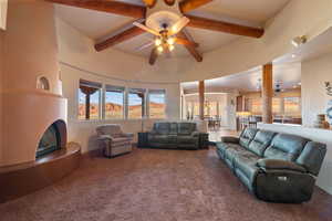 Carpeted living room with ceiling fan and beamed ceiling