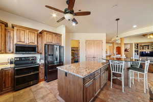 Kitchen featuring fridge with ice dispenser, pendant lighting, a center island, and range with two ovens