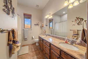 Bathroom with vanity, a shower with shower curtain, and toilet