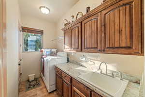 Washroom featuring cabinets, sink, and washing machine and clothes dryer