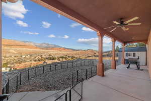 View of patio with ceiling fan, a storage shed, and a mountain view