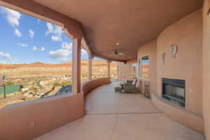 View of patio with ceiling fan, exterior fireplace, and a mountain view