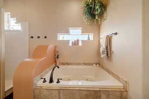 Bathroom with a relaxing tiled tub and a healthy amount of sunlight