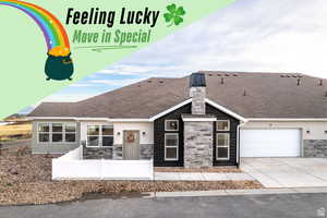 View of front of property featuring stone siding, fence, driveway, and stucco siding