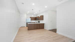 Kitchen featuring pendant lighting, sink, light hardwood / wood-style flooring, appliances with stainless steel finishes, and kitchen peninsula