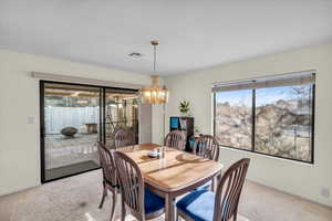 Dining space featuring carpet flooring and a chandelier