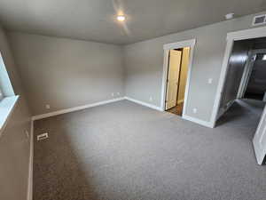 Unfurnished bedroom featuring dark carpet and a textured ceiling