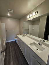 Bathroom featuring vanity, toilet, hardwood / wood-style floors, and a textured ceiling