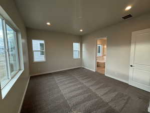 Unfurnished bedroom with dark carpet and ensuite bath