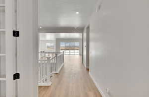 Hallway featuring light hardwood / wood-style floors and a textured ceiling