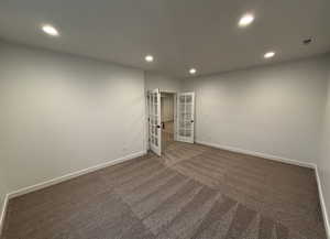 Spare room featuring french doors and dark carpet