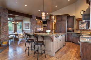 Kitchen with hardwood / wood-style floors, decorative light fixtures, sink, a kitchen bar, and a kitchen island with sink