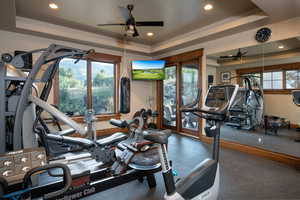 Workout area featuring ceiling fan and a tray ceiling