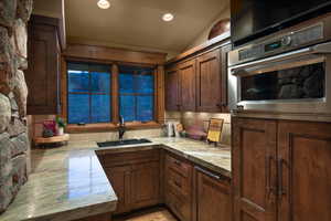 Kitchen featuring dark brown cabinetry, sink, vaulted ceiling, and oven