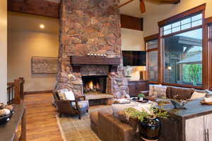 Living room featuring beamed ceiling, light wood-type flooring, a fireplace, and a towering ceiling