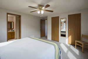 Bedroom featuring connected bathroom, ceiling fan, light colored carpet, and a textured ceiling