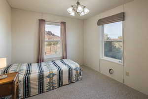 Bedroom featuring multiple windows, carpet, an inviting chandelier, and a mountain view