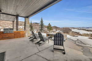 Snow covered patio with a mountain view, area for grilling, and grilling area