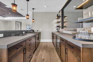 Kitchen featuring decorative light fixtures, tasteful backsplash, sink, light wood-type flooring, and a textured ceiling