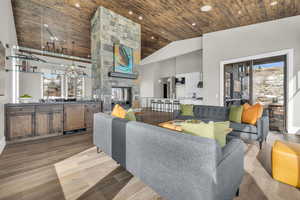 Living room featuring a fireplace, high vaulted ceiling, light hardwood / wood-style flooring, and wooden ceiling