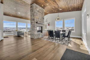 Dining area featuring a fireplace, hardwood / wood-style flooring, plenty of natural light, wooden ceiling, and an inviting chandelier