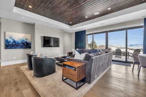 Living room featuring a tray ceiling, light hardwood / wood-style flooring, and wooden ceiling