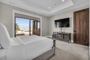 Carpeted bedroom with access to exterior and a raised ceiling