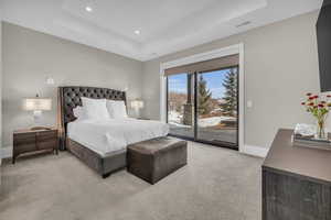 Bedroom featuring light carpet, access to outside, and a raised ceiling