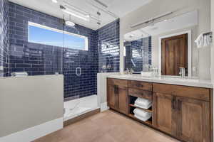 Bathroom featuring tile patterned floors, a shower with shower door, and vanity