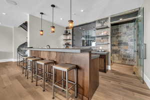 Kitchen featuring sink, a textured ceiling, a kitchen bar, decorative light fixtures, and light wood-type flooring