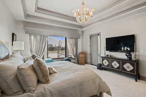 Bedroom with an inviting chandelier, carpet flooring, and a tray ceiling