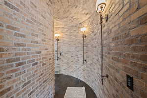 Wine area featuring hardwood / wood-style floors, brick ceiling, and brick wall