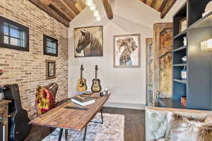 Home office featuring wood ceiling, dark wood-type flooring, lofted ceiling with beams, and brick wall