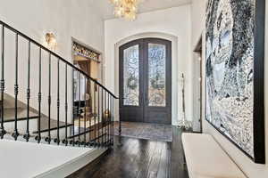 Foyer entrance with dark hardwood / wood-style flooring, french doors, and a chandelier