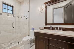 Bathroom with vanity, toilet, and a shower with shower door