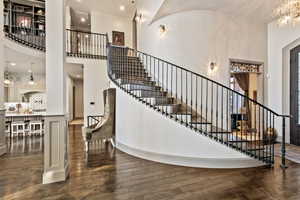 Stairway featuring a notable chandelier, sink, hardwood / wood-style floors, and a high ceiling