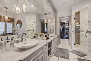 Bathroom featuring vanity, a notable chandelier, and walk in shower