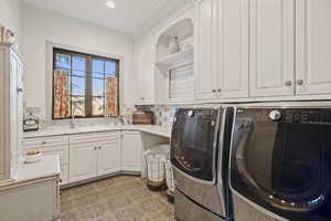 Clothes washing area featuring cabinets, separate washer and dryer, sink, and light tile patterned floors