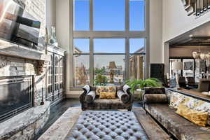 Living room featuring a stone fireplace, dark hardwood / wood-style floors, a notable chandelier, and a towering ceiling