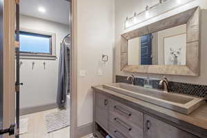 Bathroom with vanity, shower / bath combination with curtain, and decorative backsplash