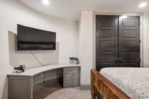 Carpeted bedroom featuring built in desk