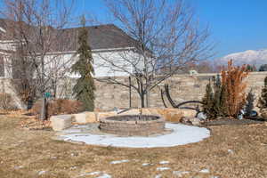 Yard layered in snow with a mountain view and a fire pit