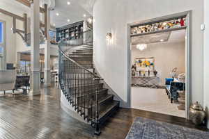 Staircase with ornate columns, wood-type flooring, a towering ceiling, and a chandelier