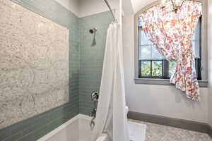 Bathroom featuring toilet and shower / bath combo with shower curtain