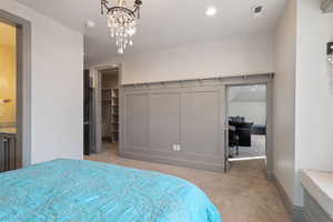 Carpeted bedroom with an inviting chandelier and a walk in closet