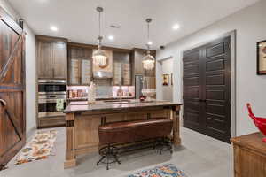 Kitchen featuring a breakfast bar, sink, stainless steel appliances, a barn door, and a center island with sink