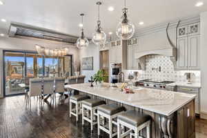 Kitchen with pendant lighting, a kitchen breakfast bar, custom range hood, and a spacious island