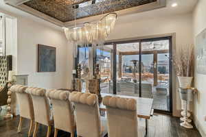 Dining space featuring dark hardwood / wood-style flooring, a raised ceiling, and a chandelier