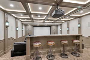 Home theater featuring beamed ceiling, indoor bar, and coffered ceiling